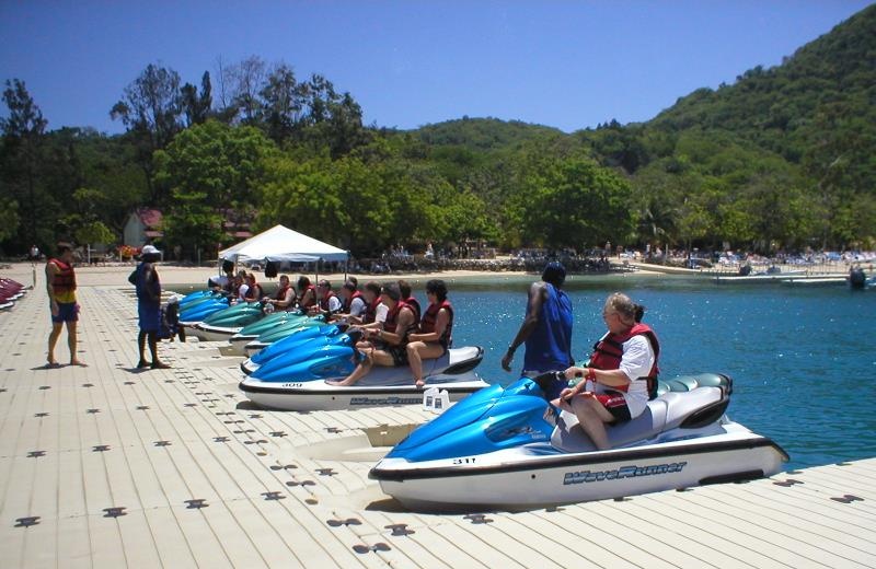 Floating Pontoon Platform For Water Sport & Jet Ski Rental Site White modular floating pontoon platform at beach resort, people preparing jet skis for water activities